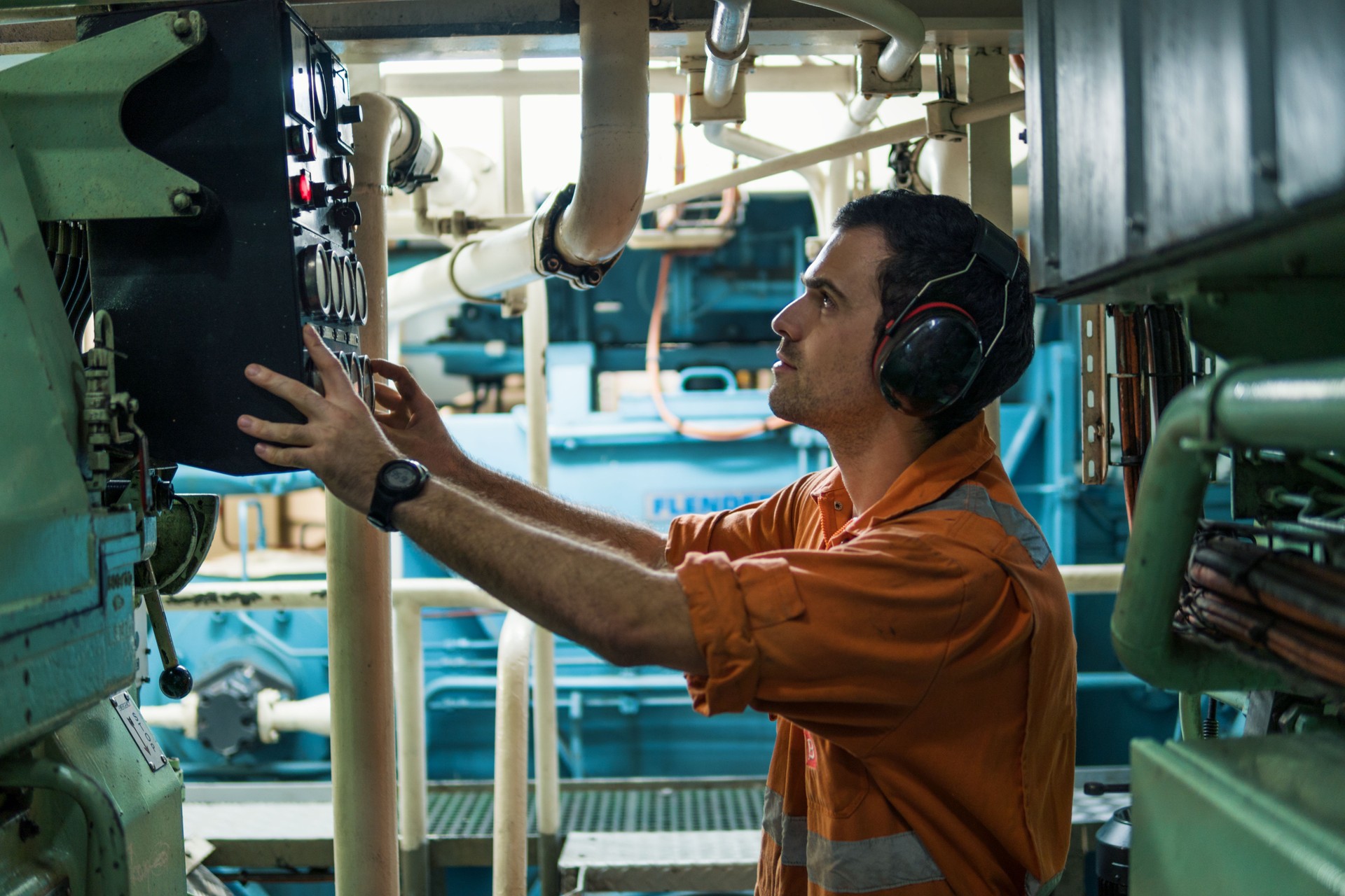 Marine engineer inspecting ship's engine in engine control room